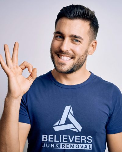 Young handsome man wearing casual t-shirt standing over isolated white background smiling positive doing ok sign with hand and fingers. Successful expression.